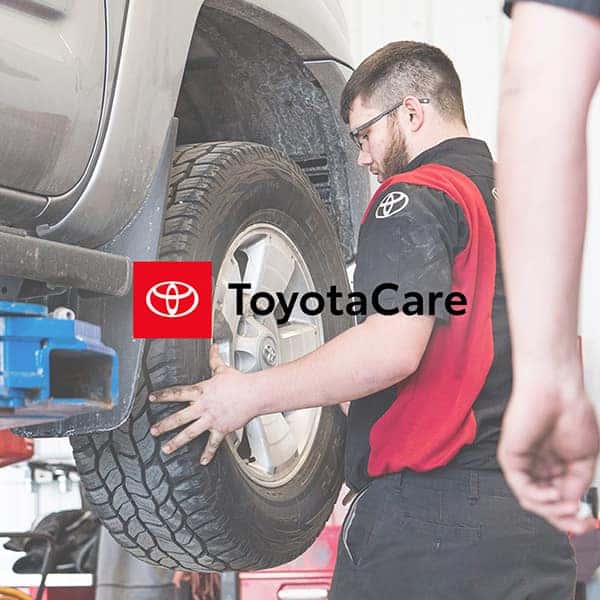 a toyota service technician preforming a tire rotation at anderson weber toyota with the toyotacare logo