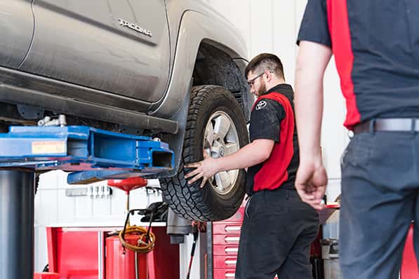 a certified toyota technician doing a tire rotation at anderson weber toyota service department
