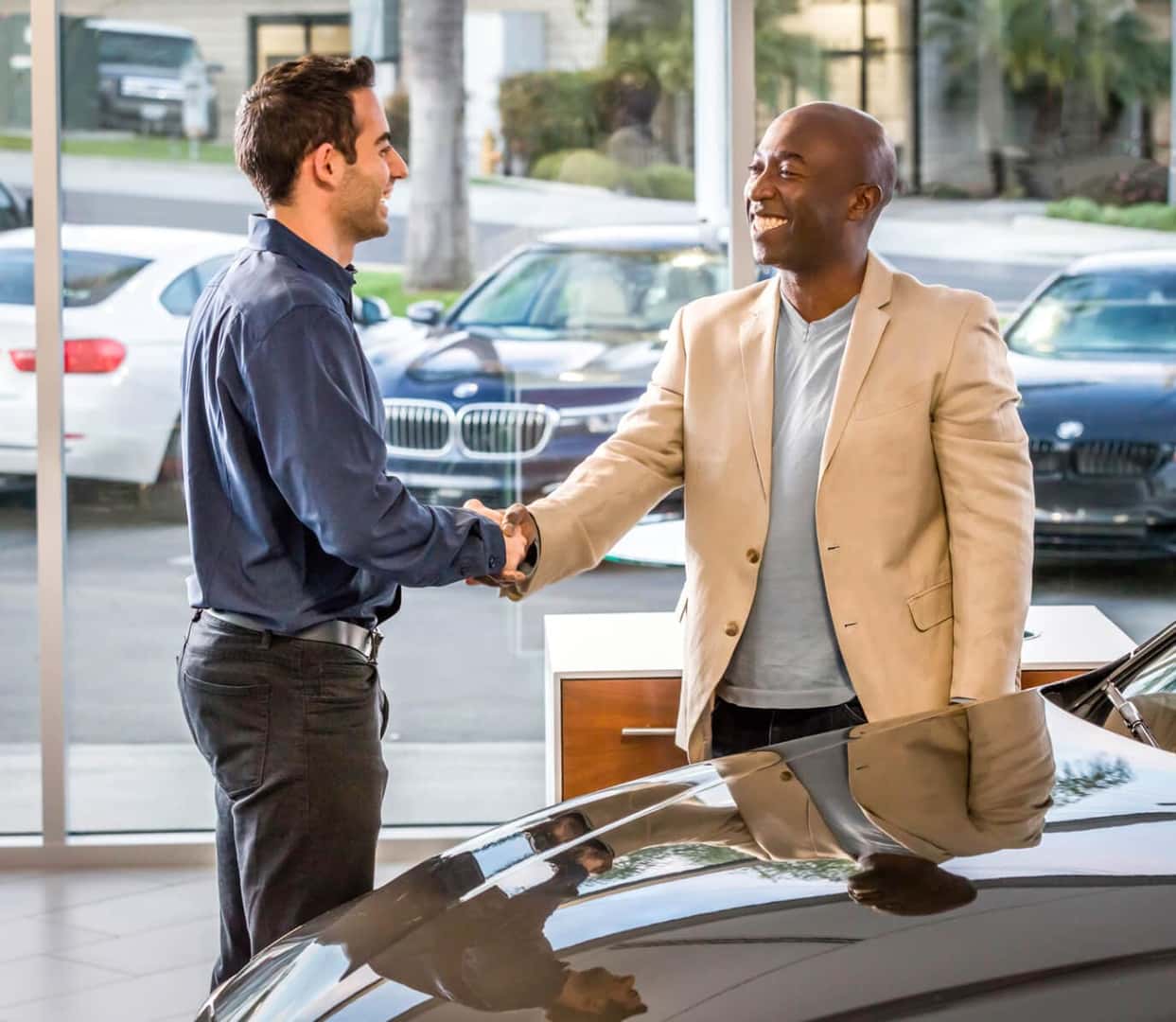 Happy customer shaking hands with car dealer