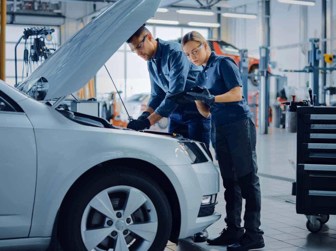 Two auto mechanics inspecting engine during vehicle maintenance service