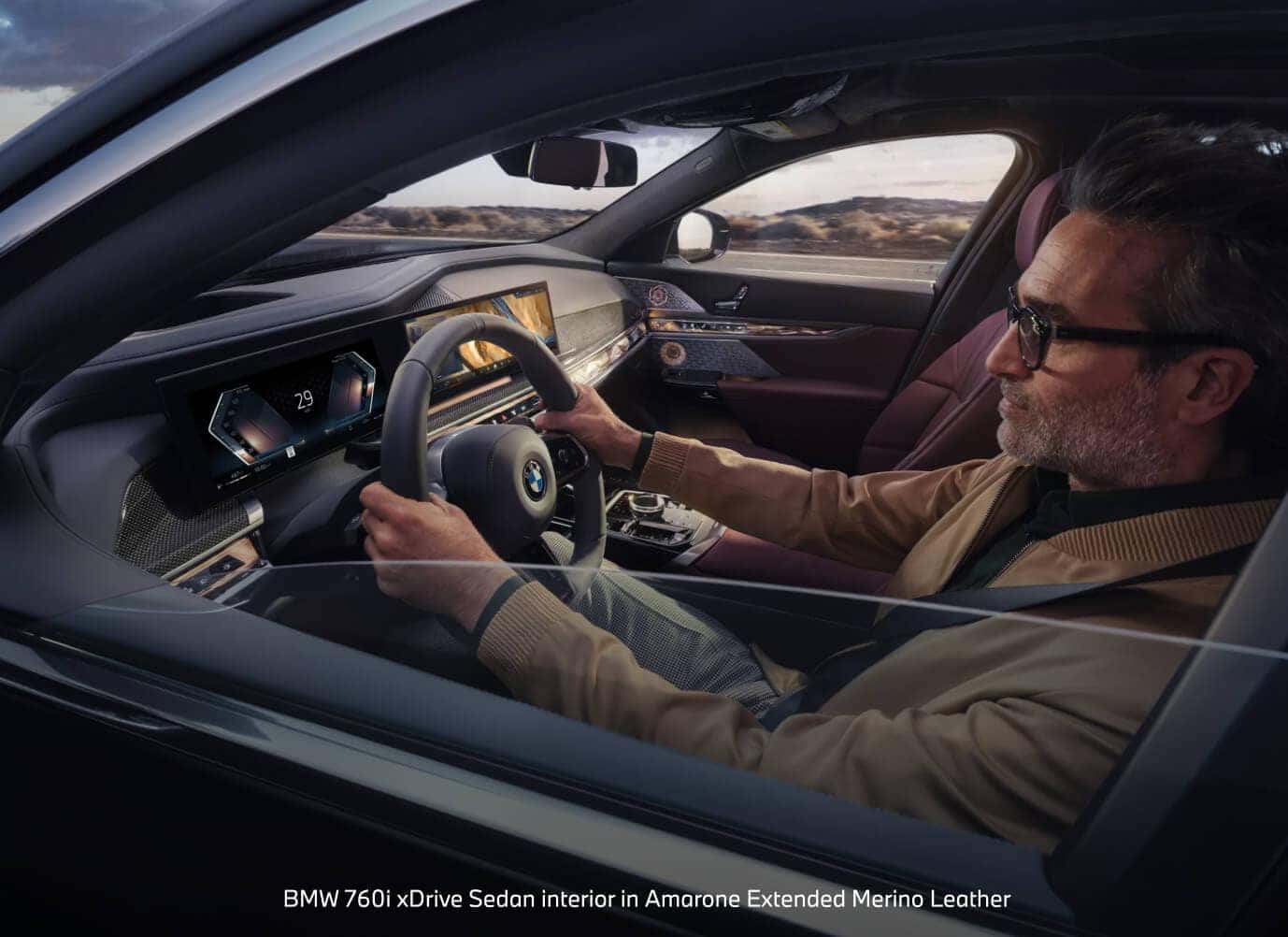 BMW 760i xDrive Sedaninterior in Amarone Extended Merino Leather with curved display dashboard on a highway route.