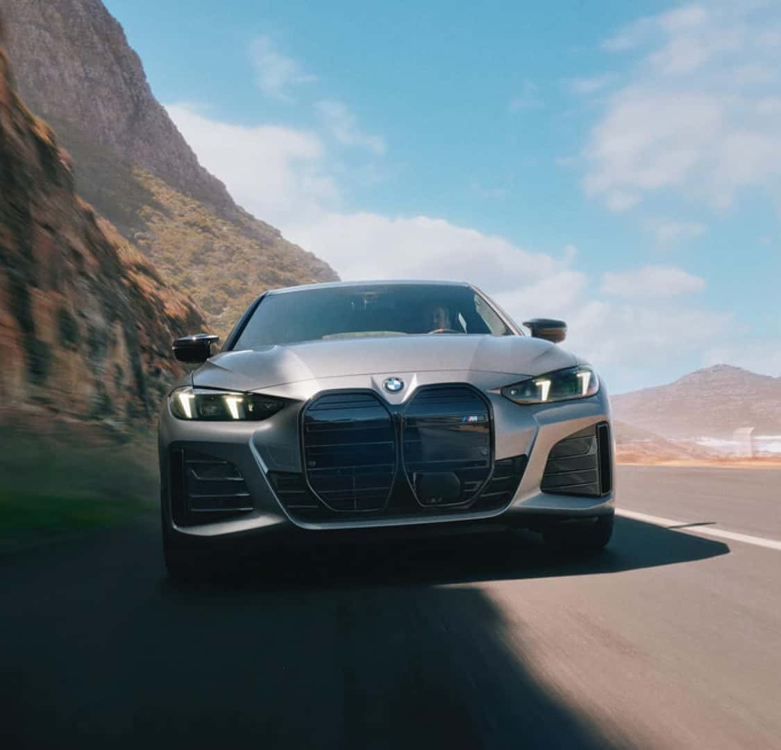 A 2026 BMW i4 drives down a coastal road