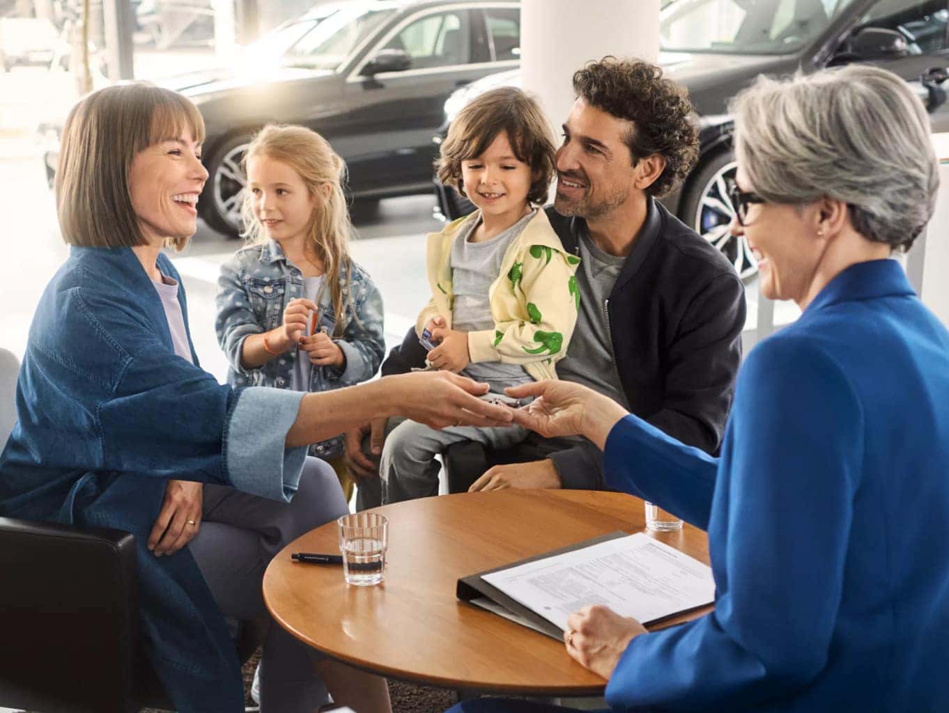 A BMW financial services agent hands a BMW key to a smiling family
