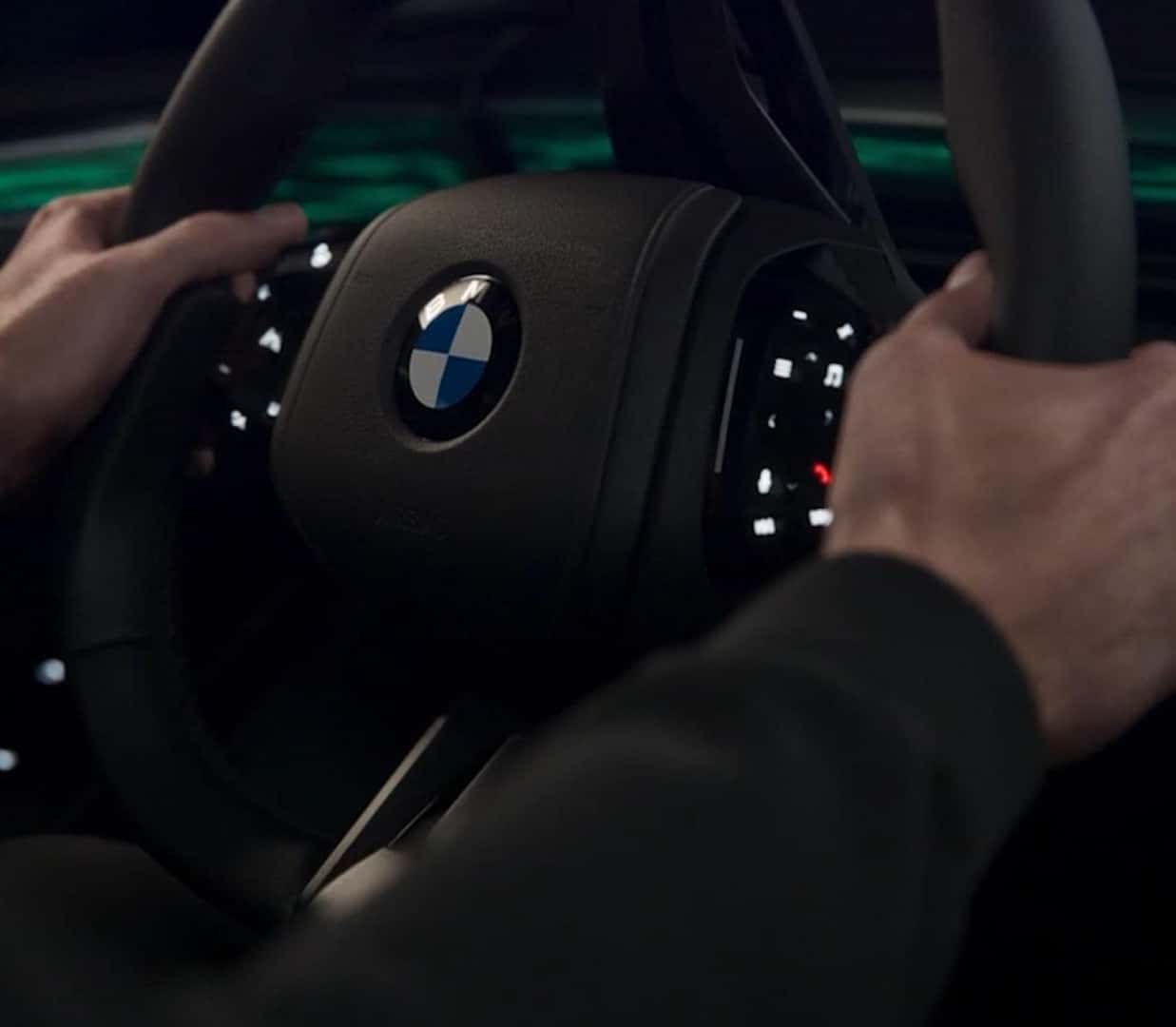 Close-up of the BMW X5 steering wheel with integrated controls and ambient interior lighting in the background.