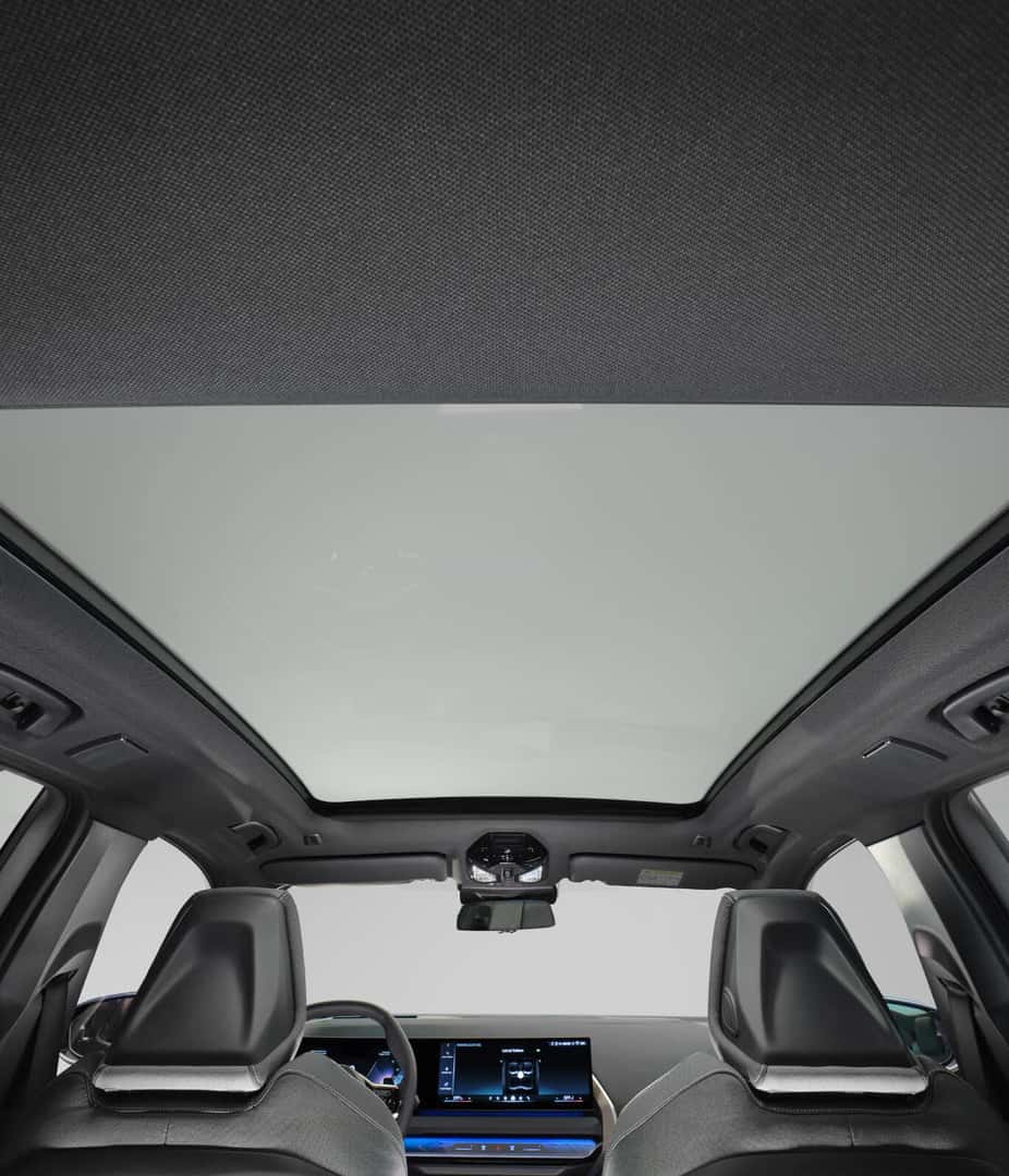 Interior view of front seats and panoramic glass sunroof inside a BMW X3 cabin.