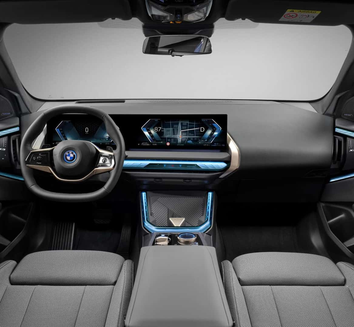 Interior dashboard view of BMW X3 featuring curved display and steering wheel.