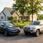 Dark blue Honda CR-V and silver Toyota Tacoma parked in a driveway in front of a house. (Representative image for illustration purposes only. Actual vehicle may vary based on trim and configuration.)