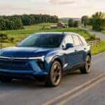 A blue Chevrolet Blazer EV driving around a curve on a scenic country road at sunset. (Representative image for illustration purposes only. Actual vehicle may vary based on trim and configuration.)