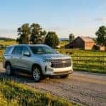Silver Chevrolet SUV driving down a rural paved road past a farm with a red barn and cattle. (Representative image for illustration purposes only. Actual vehicle may vary based on trim and configuration.)