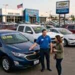 used cars at a chevy dealership lot with a sales person looking over a car with a customer (Representative image for illustration purposes only. Actual vehicle may vary based on trim and configuration.)