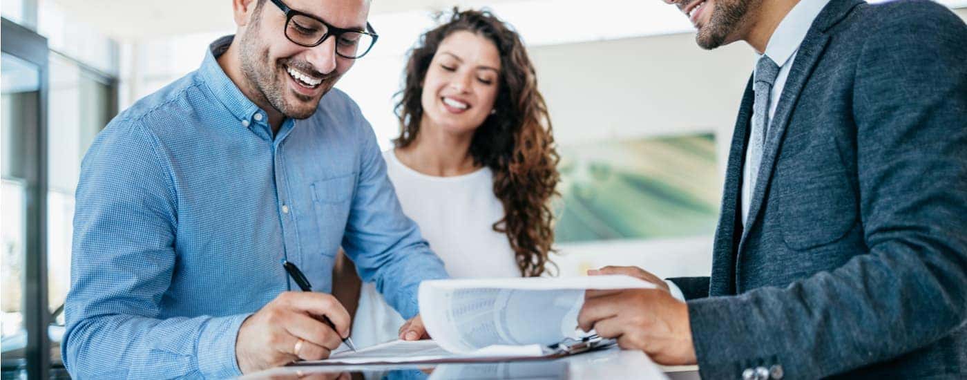 A couple is shown going over financing paperwork at a car dealership.