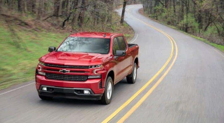 A red 2019 Chevy Silverado RST is shown from a high angle driving down a winding road.