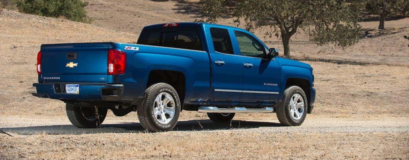 A blue 2018 Chevy Silverado 1500 is shown from the side parked in a field.