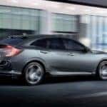 A grey 2021 Honda Civic Hatchback Sport Touring is shown from the side driving through a city.