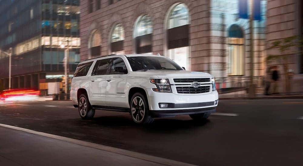 A white 2020 Chevy Suburban is shown driving on a city street after viewing used SUVs Near Cary, NC.
