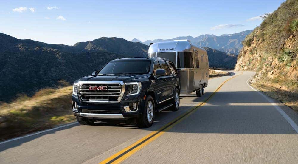 A black 2021 GMC Yukon is shown towing a trailer.