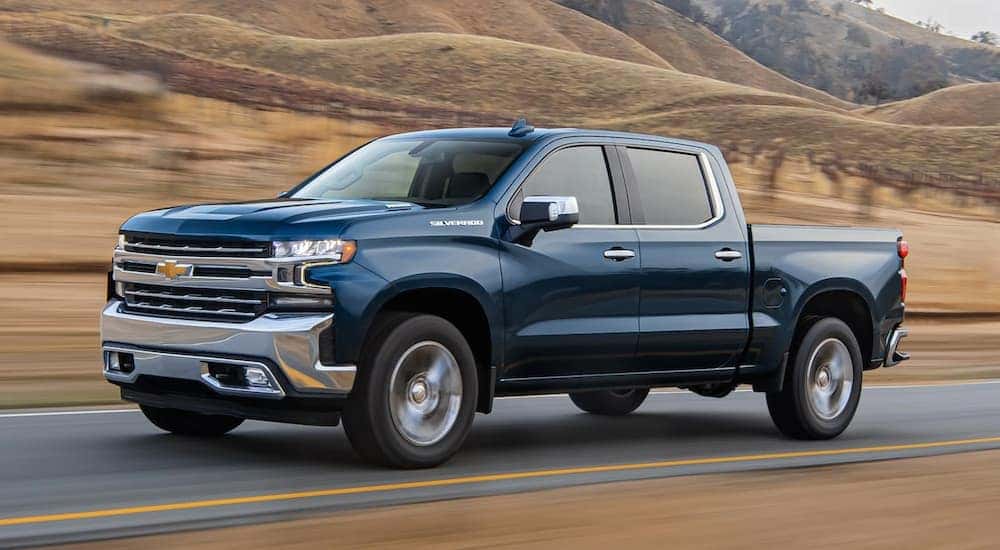 A blue 2020 Chevy Silverado 1500 is shown driving on a highway.