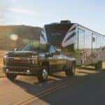 A 2021 Chevy Silverado 3500 towing a large camper on the highway.