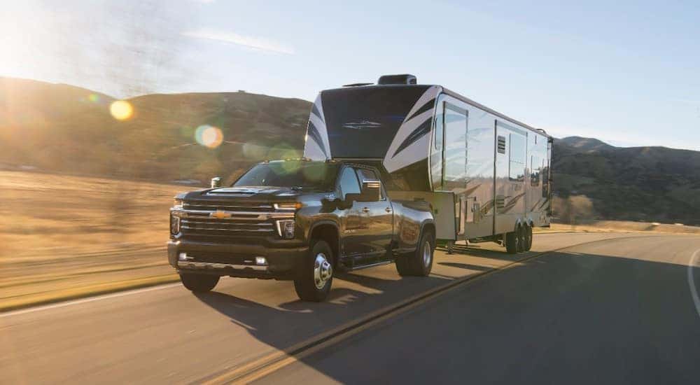 A 2021 Chevy Silverado 3500 towing a large camper on the highway.