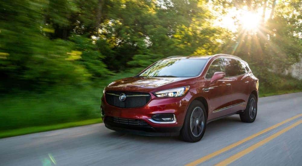 A red 2020 Buick Enclave Sport Touring driving on a sunny road.