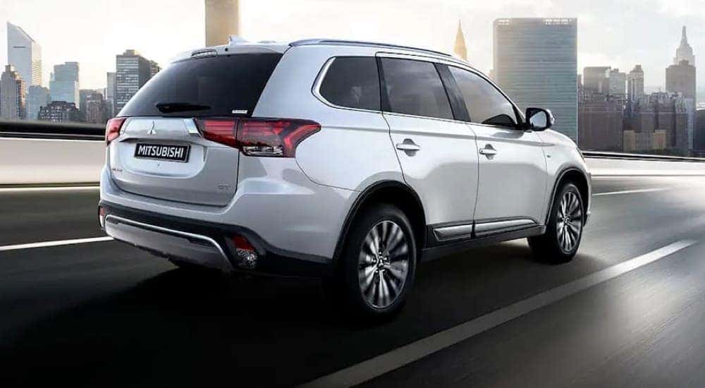 A white 2020 Mitsubishi Outlander, one of many used SUVs for sale, driving near a city.