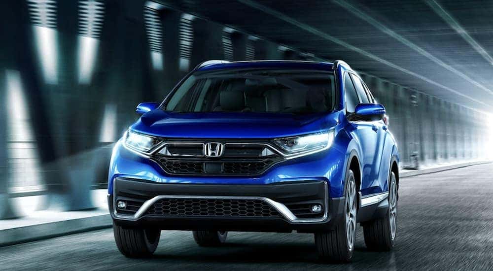 A blue 2022 Honda CR-V Touring driving in an illuminated tunnel.