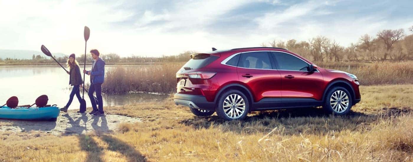 A red 2020 Ford Escape is shown parked near two people and a kayak.