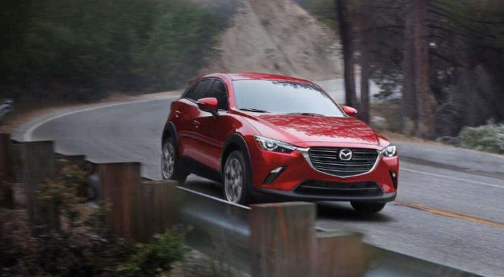 A red 2020 Mazda CX-3 is shown driving on a highway to view used cars for sale near Chapel Hill.