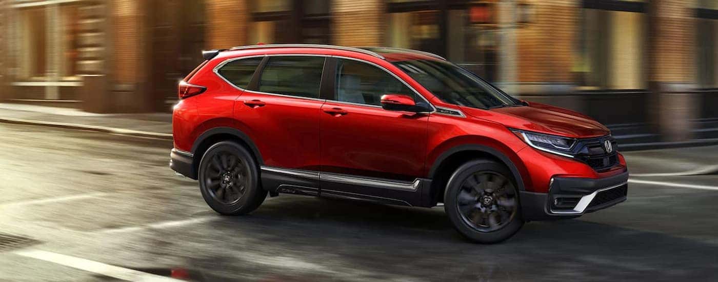 A red 2021 Honda CR-V Touring is shown driving on a city street.
