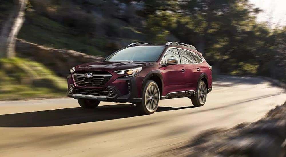 A purple 2023 Subaru Outback is shown driving off-road.