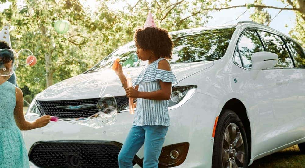 Kids walking past a parked white 2020 Chrysler Pacifica.