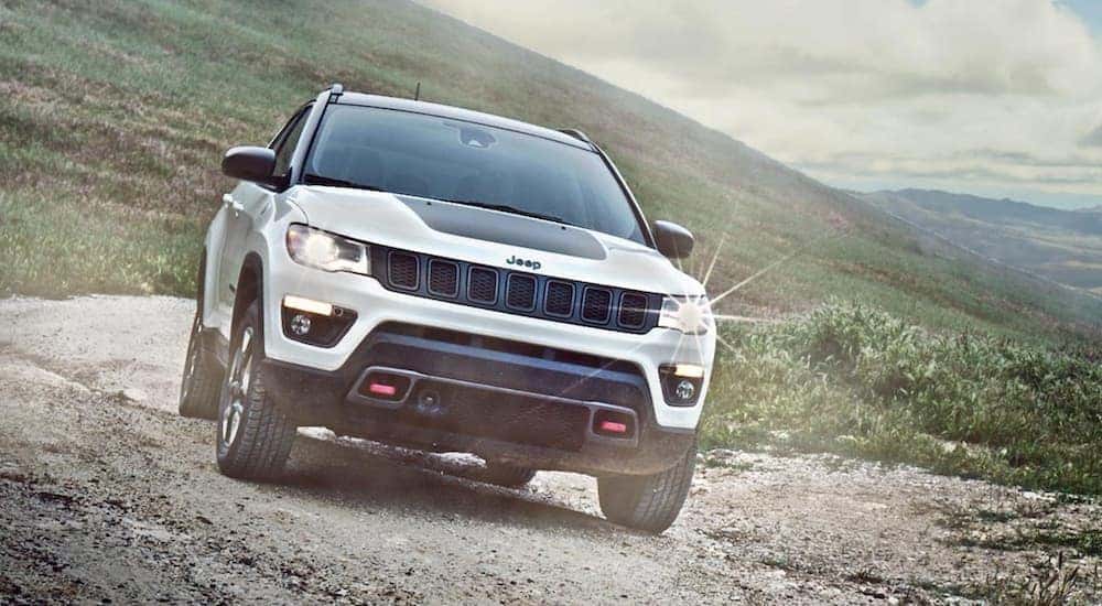A white and black 2020 Jeep Compass Trailhawk driving down a trail.