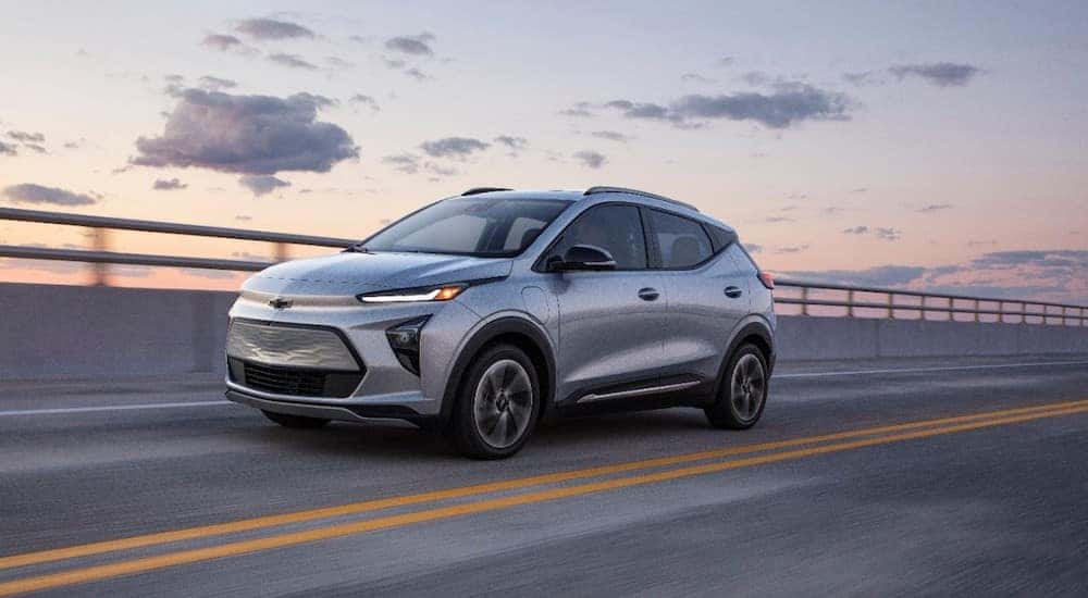 A silver 2022 Chevy Bolt EUV driving across a bridge from a dealer with used cars for sale near Wake Forest.