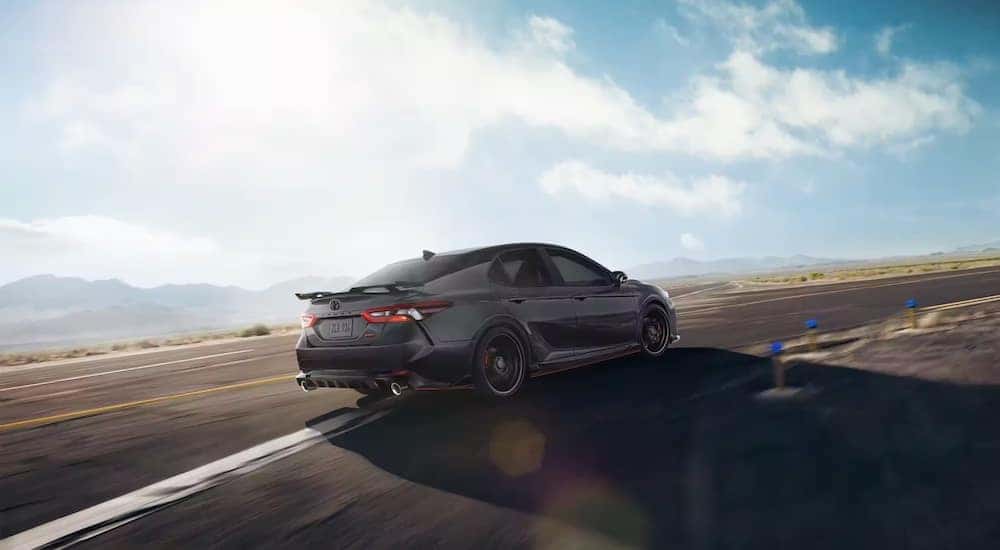 Rear view of a dark grey 2021 Toyota Camry TRD driving on a racetrack.