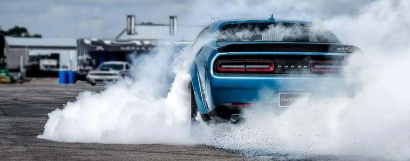 A blue 2020 Dodge Challenger Hellcat performing a burnout.