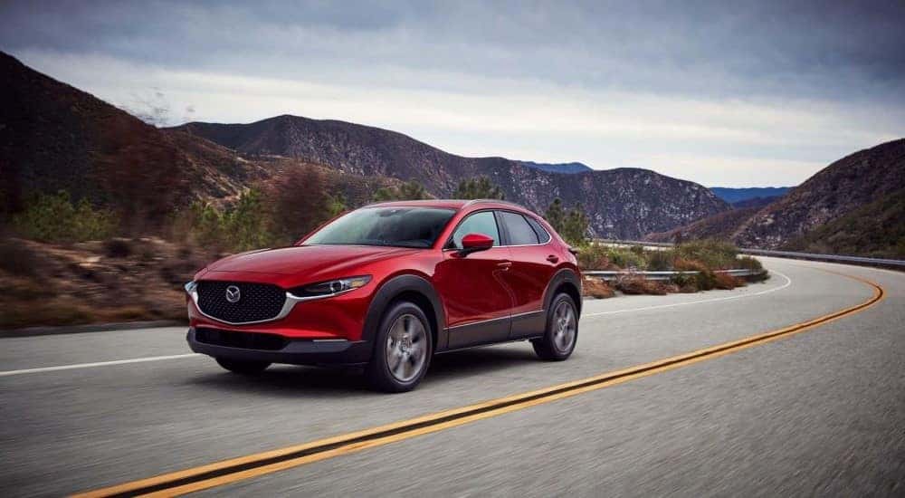 A red 2020 Mazda CX-30 driving around a bend.