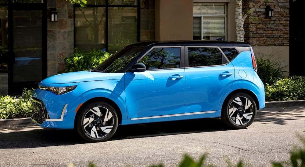 A blue 2023 Kia Soul parked by a curb.