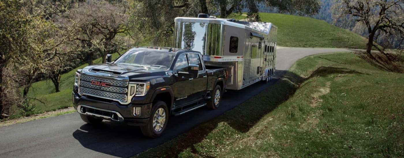 A black 2021 GMC Sierra 2500 HD Denali towing a camper van.