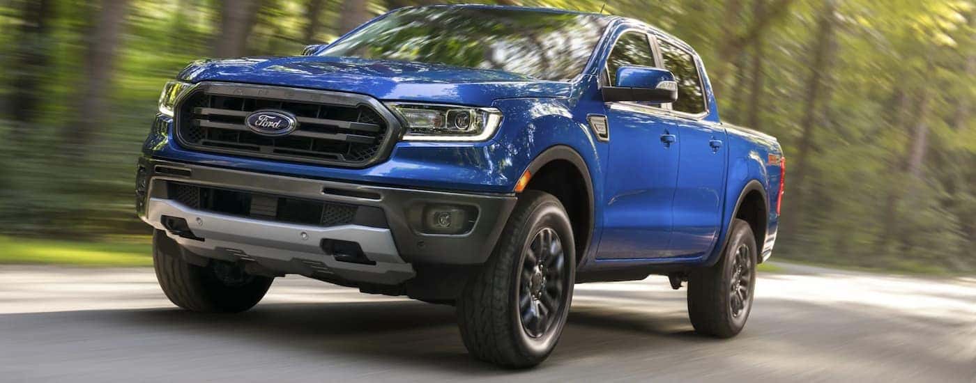 A blue 2021 Ford Ranger FX4 is shown driving on a back road.