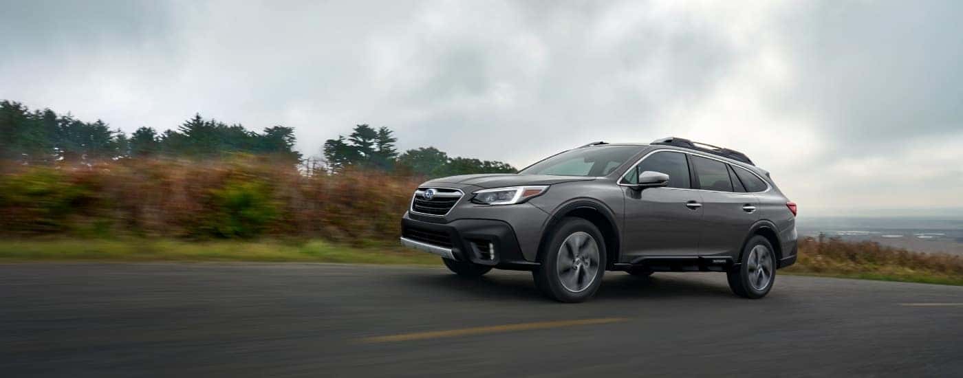 A grey 2020 Subaru Outback is shown driving on a cloudy day.