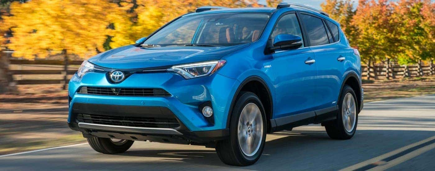 A blue 2016 Toyota RAV4 driving down a road.
