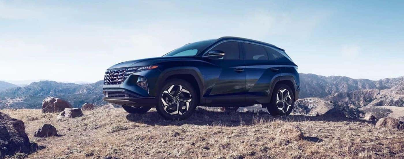 Side angle view of a dark blue 2023 Hyundai Tucson Hybrid Limited parked off-road.
