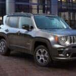 A silver 2023 Jeep Renegade parked near a car dealership.