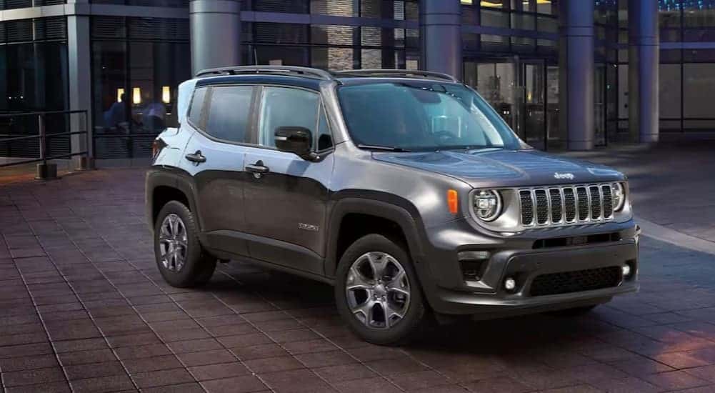 A silver 2023 Jeep Renegade parked near a car dealership.
