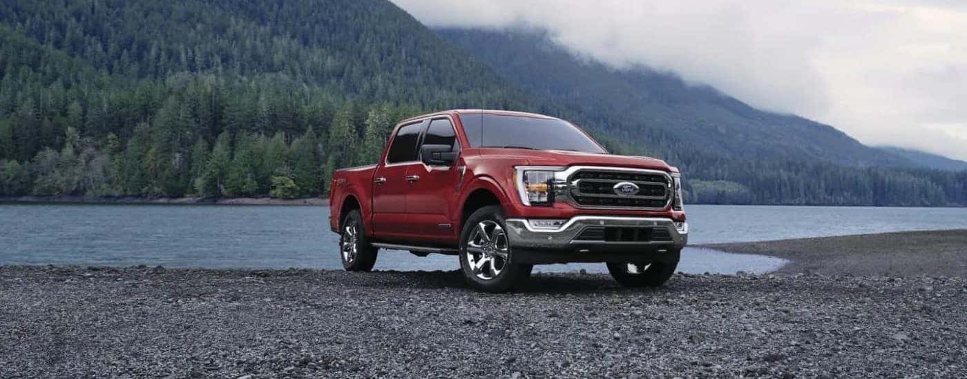 A red 2023 Ford F-150 parked near a lake