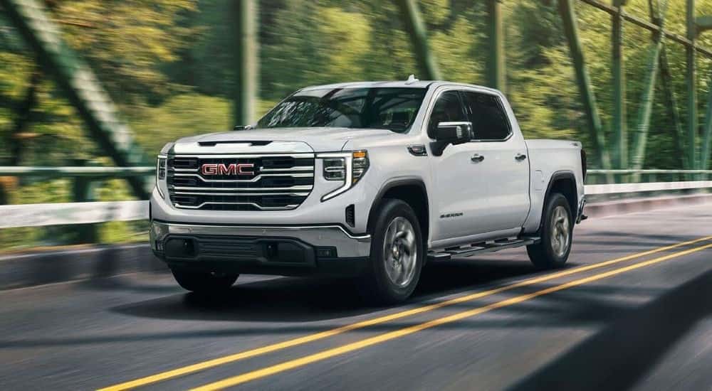 A white 2024 GMC Sierra 1500 SLE driving down a road