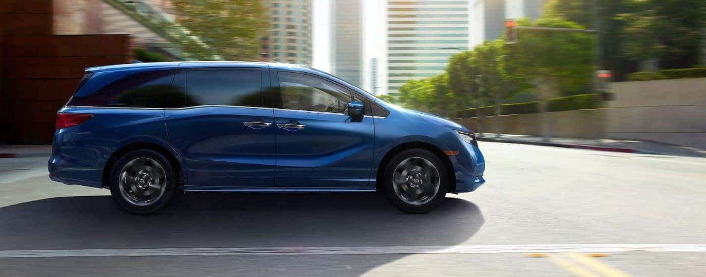 A blue 2025 Honda Odyssey driving in a city