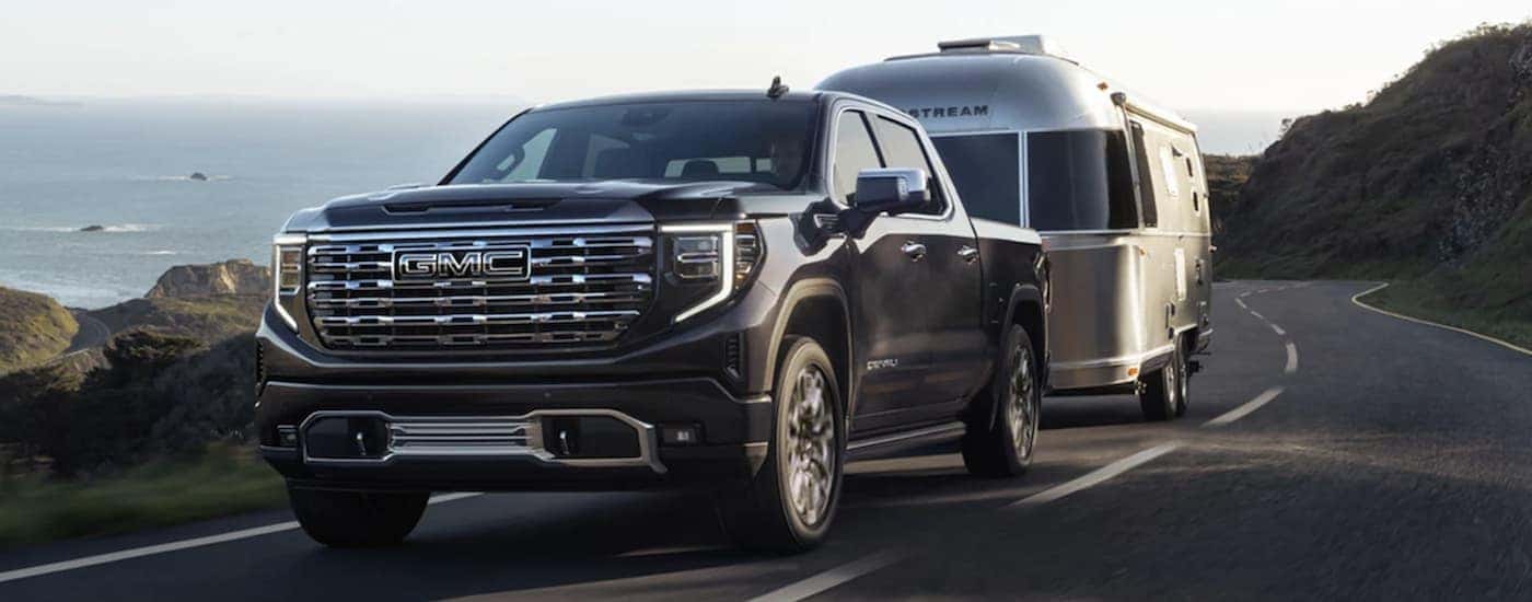 A black 2023 GMC Sierra 1500 Denali towing an Airstream camper
