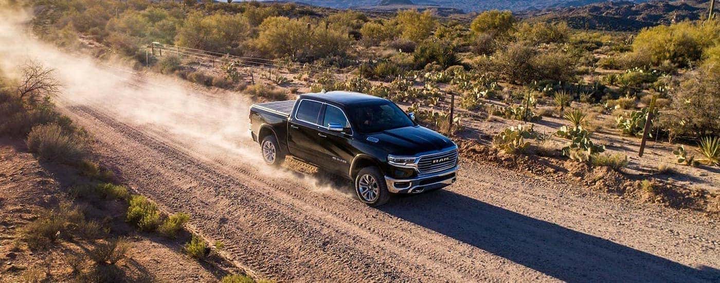 A black 2019 Ram 1500 is shown driving through a dusty trail