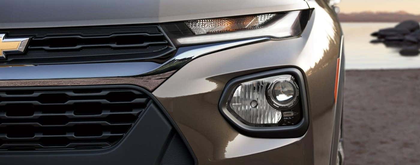 A close up of the front of a brown 2022 Chevy Trailblazer shows the driver's side headlight